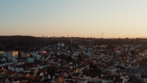 Aerial-view-of-houses-in-town-neighbourhood.-Rising-footage-reveals-panorama-of-skyscrapers-in-Frankfurt-am-Main-against-twilight-sky.-Bad-Vilbel,-Germany.