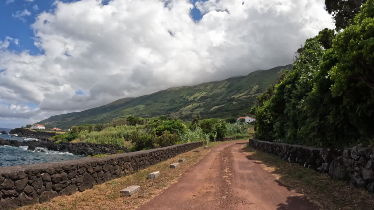 Driving POV along a coastal road with scenic view of Pico Island's lush hills