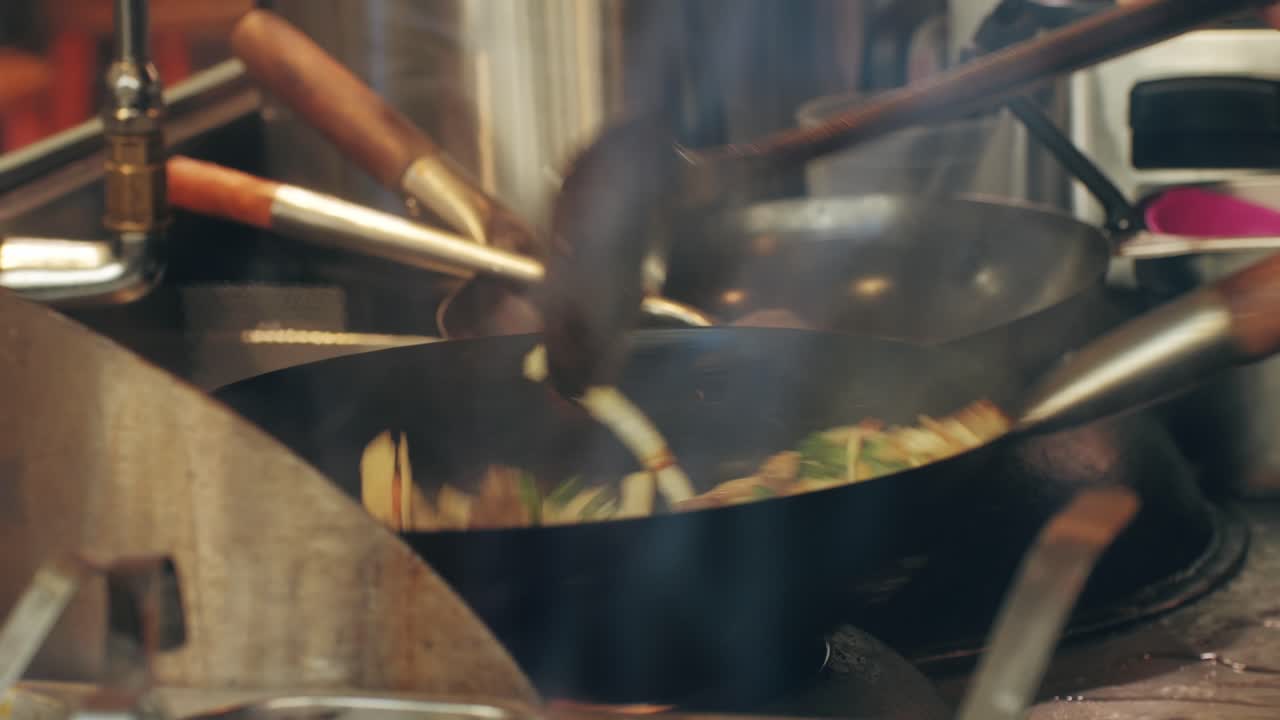 A dynamic cooking scene is showcased with vibrant flames and skilled hands actively working in a lively kitchen setting