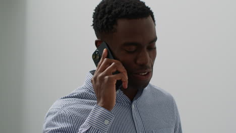 close up of smiling young businessman walking along corridor in office talking on mobile phone 2