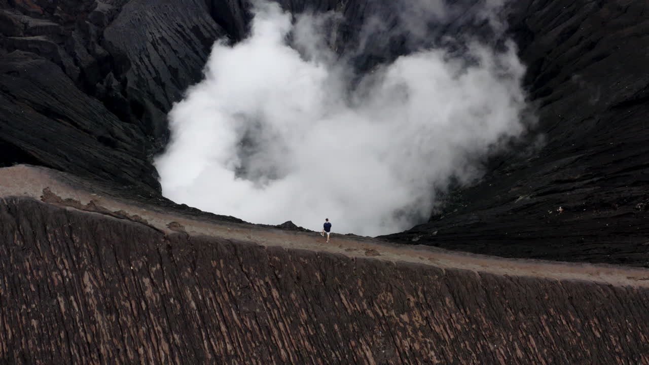 Man standing on edge of active Volcano Mt. Bromo in East Java, Indonesia