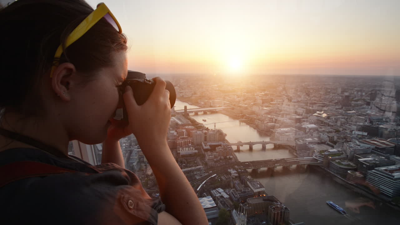 turista tomando una fotografía de la puesta de sol en el horizonte de londres vista desde el fragmento