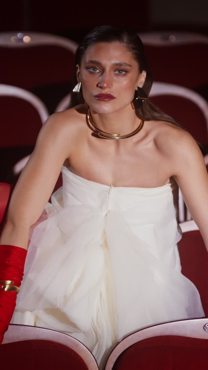 Donna in abito bianco e guanti rossi a teatro