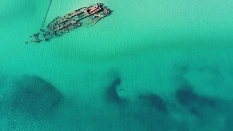 Aerial-shot-by-drone-of-a-shipwrecked-ship-very-close-to-a-beach-in-Epanomi,Thessaloniki-with-blue-water-in-Greece
