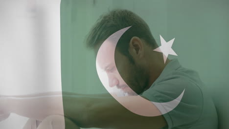 sitting with head down, man overlaid by pakistan flag, conveying contemplation