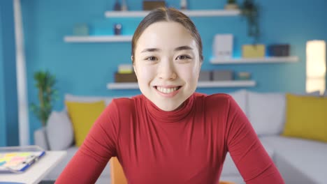 asian young woman is starting to rejoice at what she sees while looking at laptop and looking at camera.