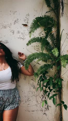 woman by a wall with ferns