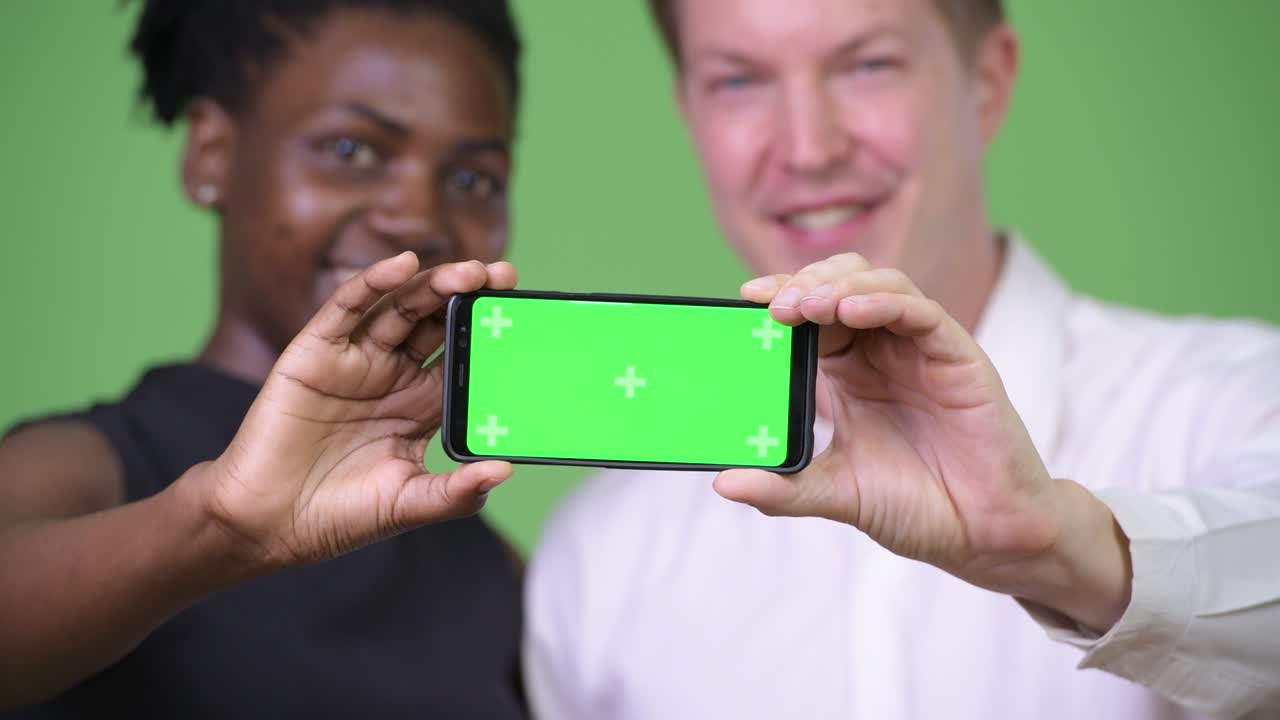 dos jóvenes parejas de negocios multiétnicos mostrando el teléfono juntos