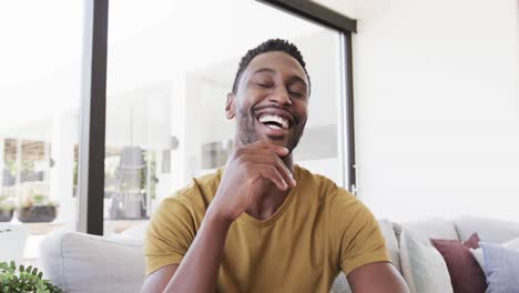 portrait of happy african american man making video call, talking and laughing, in slow motion