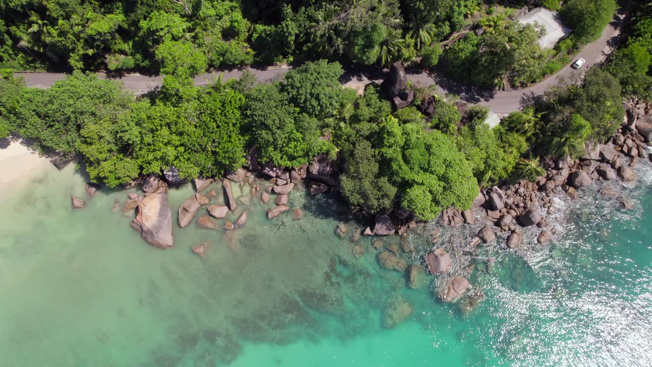 Rekaman drone klien berenang dan snorkeling dekat batu granit, dikelilingi pohon, air biru kehijauan, Anse Louis, Mahe Seychelles 30 fps