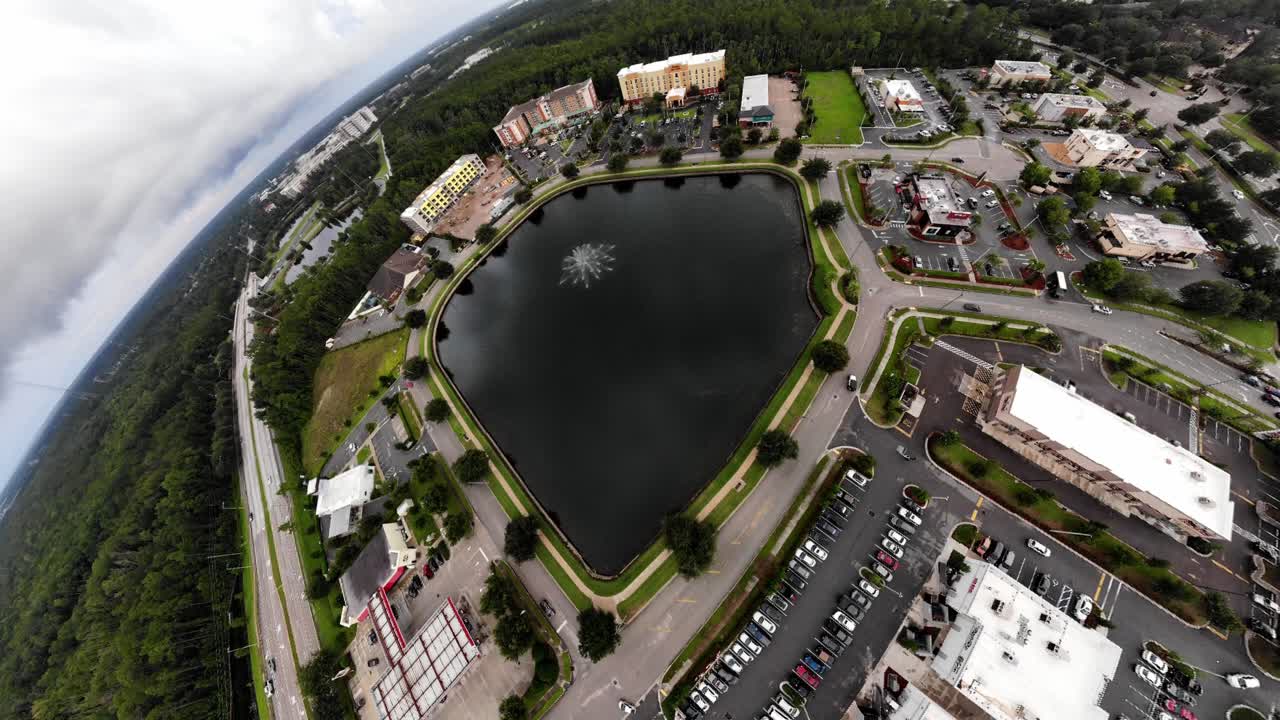 hermoso zoom aéreo de la fuente de agua en los edificios del estanque en el fondo árboles en primer plano