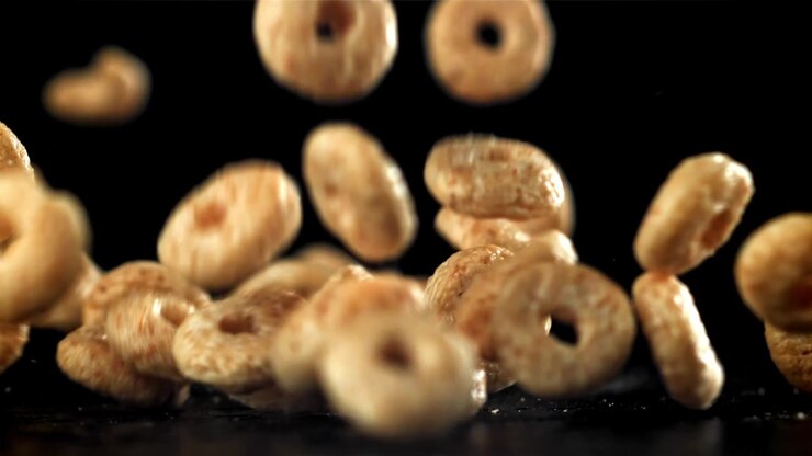 Anelli di cereali dorati che cadono al rallentatore su sfondo nero