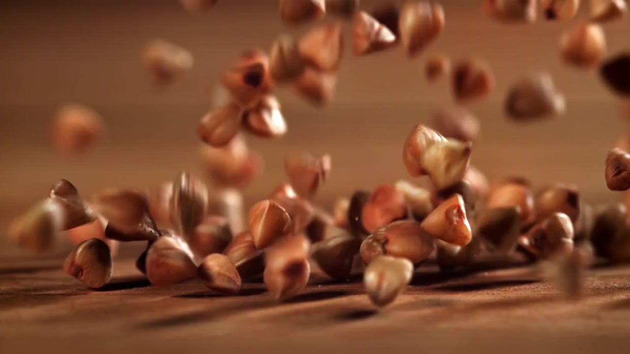Raw Buckwheat Grains Falling in Slow Motion onto a Wooden Background