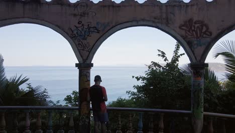 joven turista mirando la ciudad costera de jaco desde el miro, un antiguo hotel abandonado en costa rica