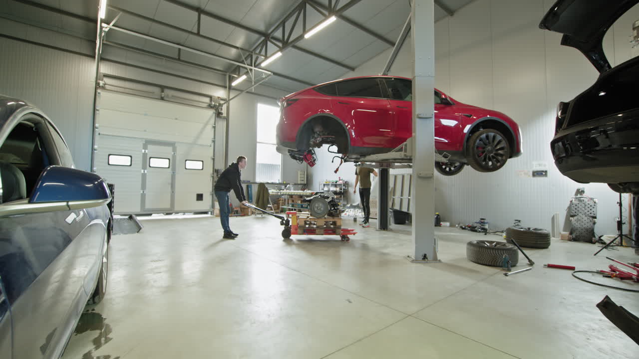 reparación de automóviles en garaje con vehículo eléctrico levantado