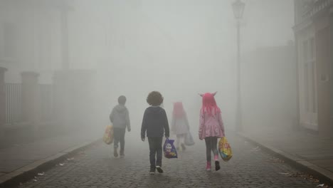 a haunting misty walk: children with halloween bags journeying through an enigmatic foggy street in a mysterious atmosphere
