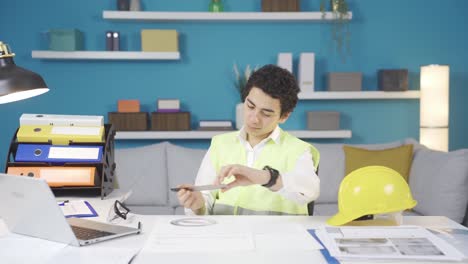 Boy-in-helmet-and-vest-dreams-of-being-an-engineer-at-home-at-his-father's-desk.