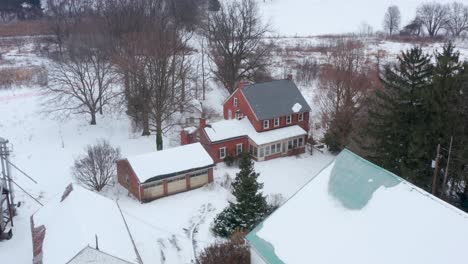 aerial of family farm, farmhouse home covered in winter snow