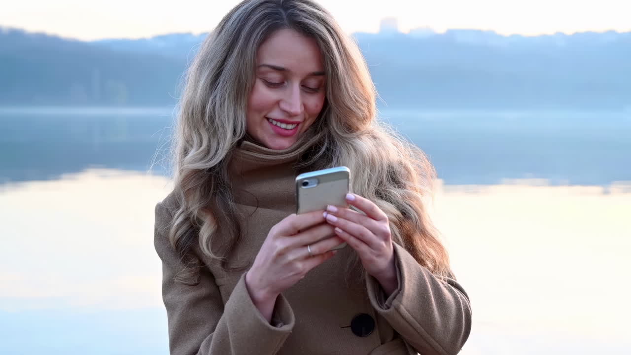 Smiling young woman typing in her phone in park
