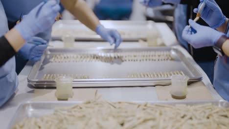 manufacture workers applying infusion of kief on pre-roll joints, cannabis facility, tracking out shot