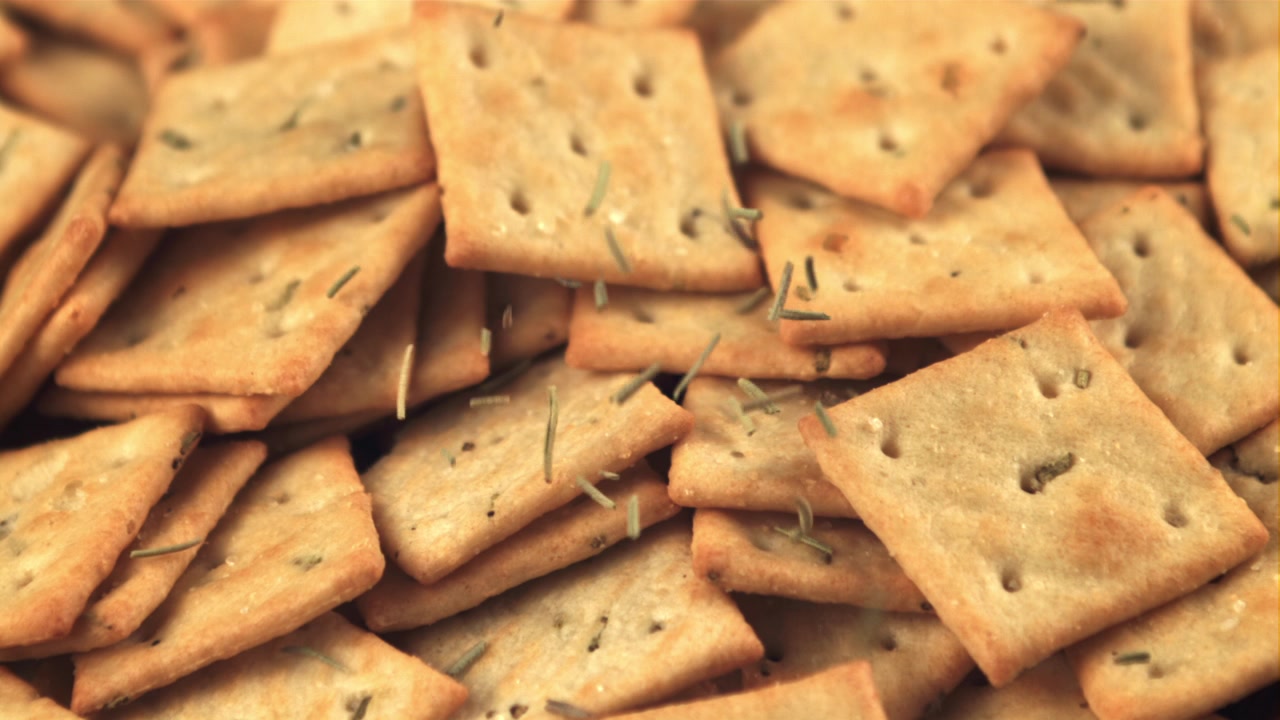 Rosmarino che si sparge su cracker salati al rallentatore.