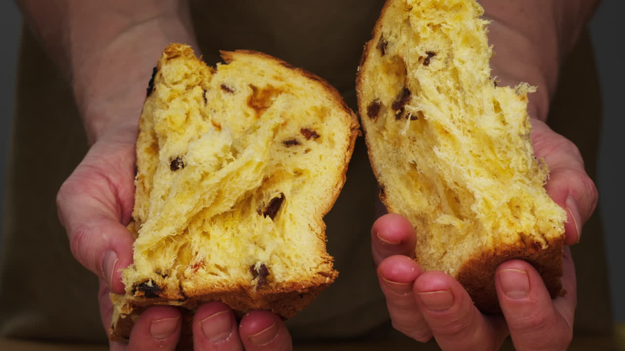 Traditional English Christmas cake tied with a jute thread on the black background. Italian classic Panettone .Pastry Chef sprinkles powdered sugar through a sieve on the fruit Easter cake with raisins. High quality 4k footage