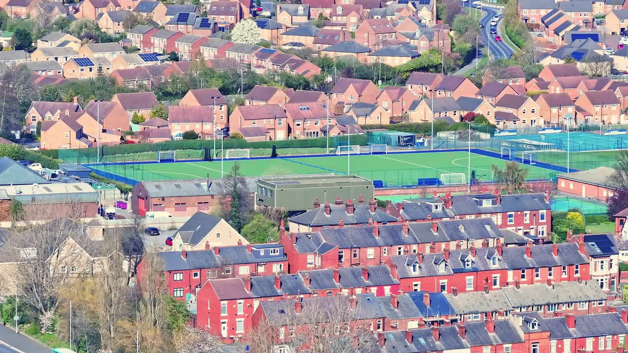 Aerial view of Soccer field surrounded by residential suburban housing in Wakefield, Yorkshire, Northern England. A vibrant and middle-class community. Traditional British red brick homes.