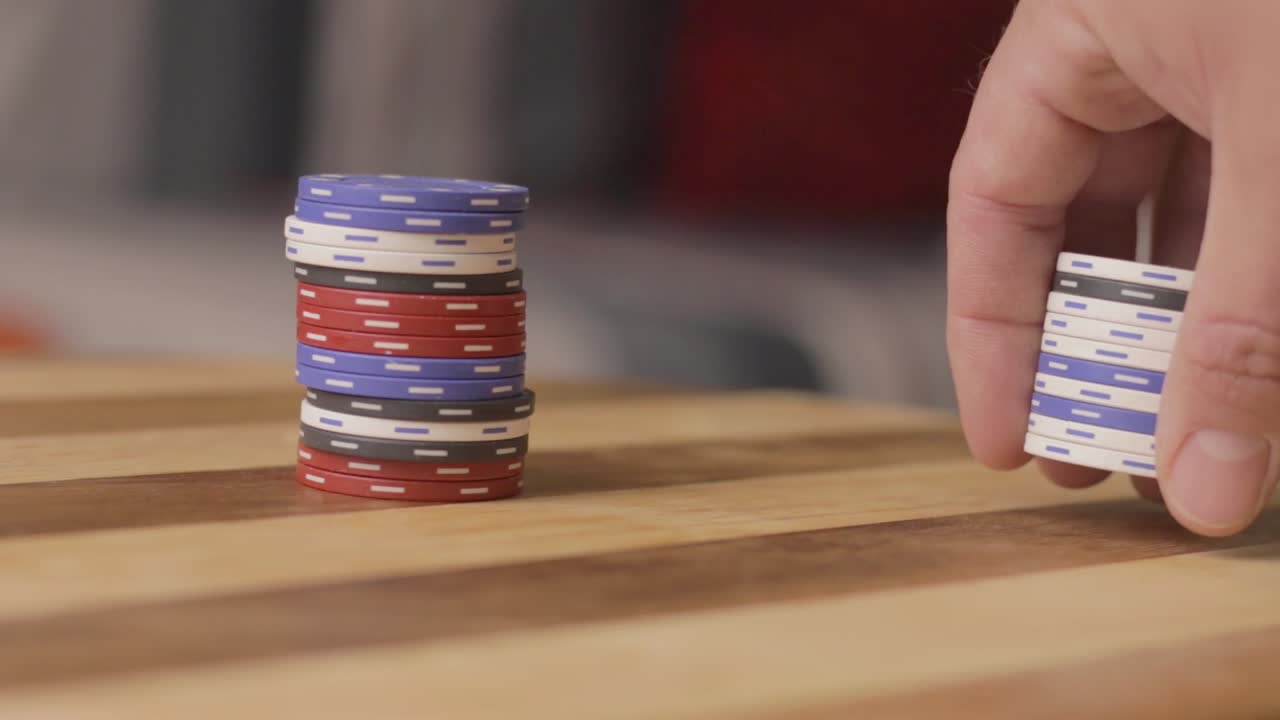 pan left close up of man counting poker chips and pushing it to another stack of chips