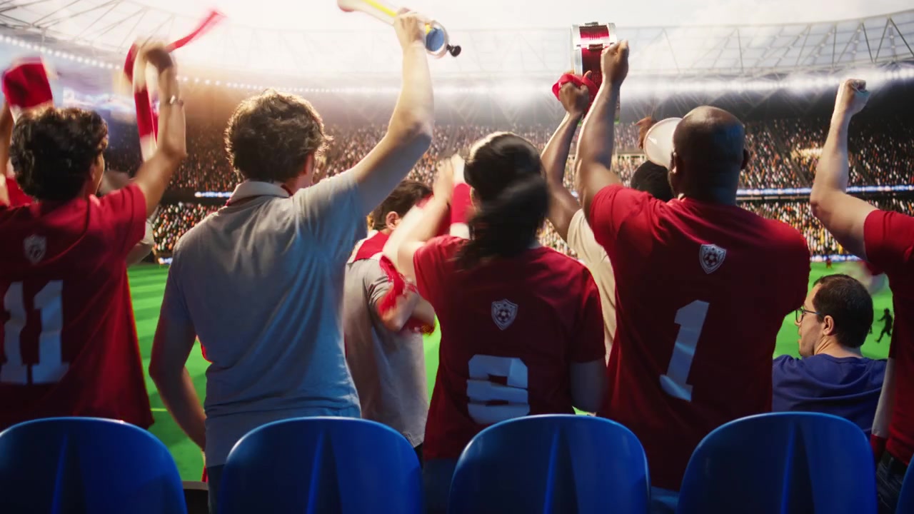 Aficionados al fútbol con camisetas rojas tocan vuvuzelas, caminando en el estadio