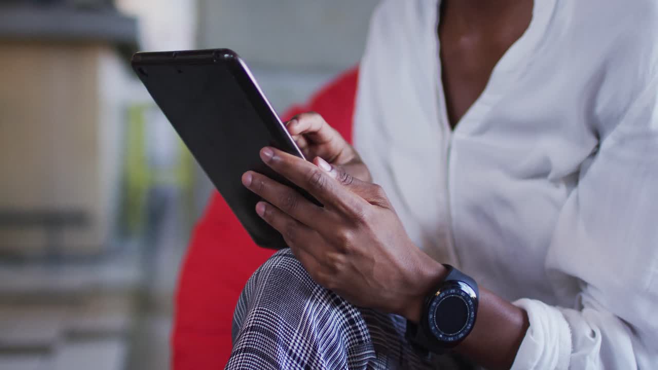 Happy african american woman sitting in cafe using digital tablet and smiling