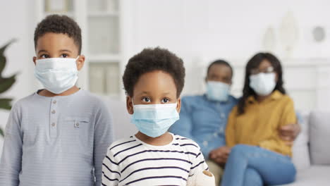 portrait of small kids in medical masks looking at camera at home