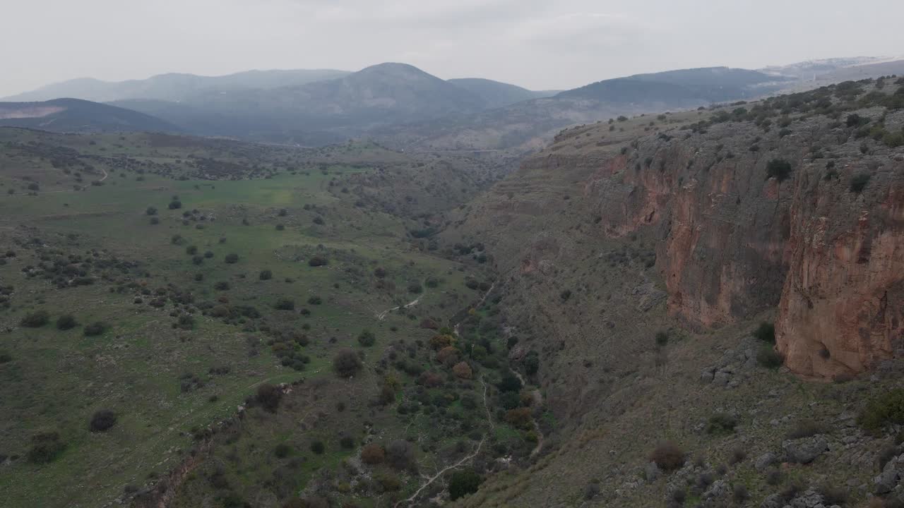 Veduta aerea in sorvolo di un escursionista che scala il fianco roccioso di una montagna sopra la valle, Israele.