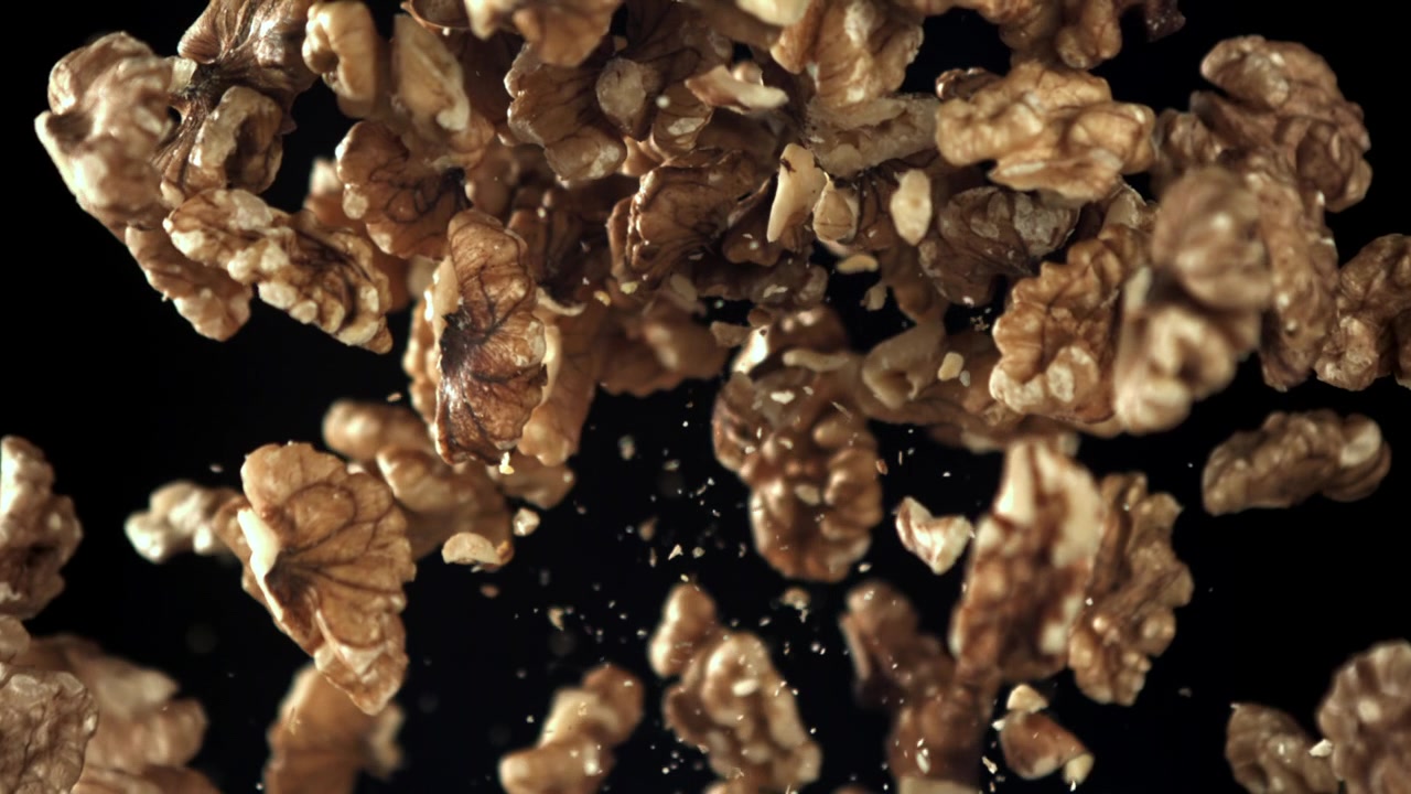 Shelled Walnuts Flying in Super Slow Motion on Black Background