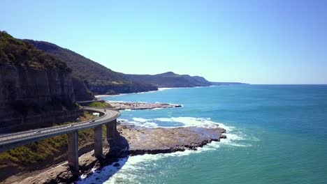 las imágenes aéreas de un impresionante puente largo y curvo junto al mar resaltan el gran paseo pacífico con el océano pacífico sur y la vista del cielo azul en un día soleado, sydney, australia