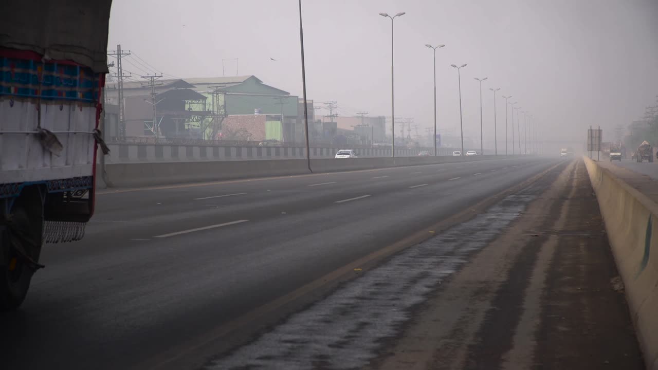 겨울철 안개가 자욱한 계절에 도로 위의 트럭, 자동차, 오토바이, 투표소, 벽, 간판, 도로가 있는 공장