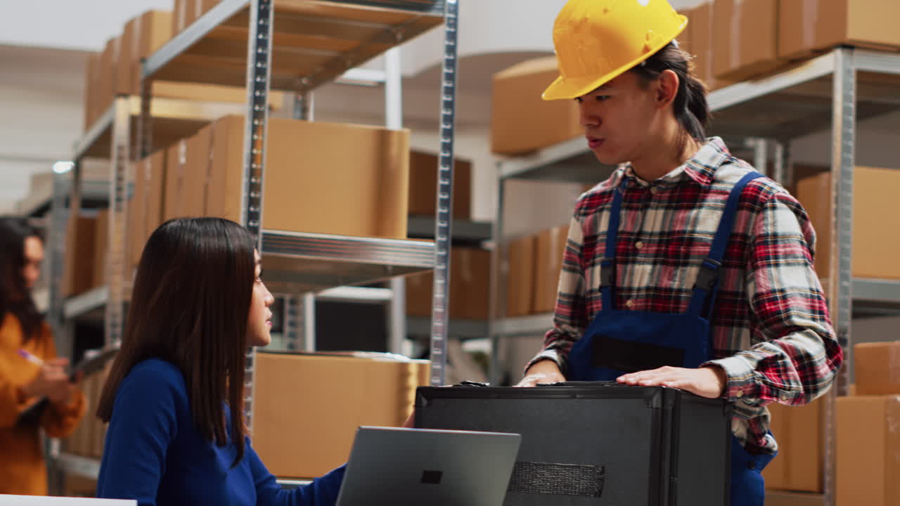 Warehouse workers discussing inventory with laptop and boxes