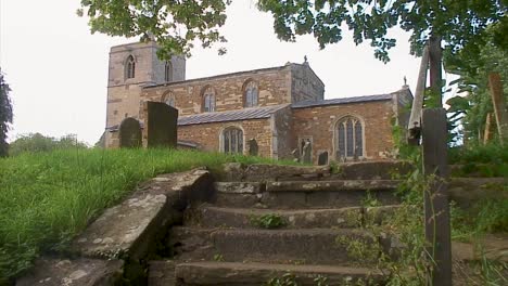 viejos escalones de piedra que conducen a la antigua iglesia inglesa del siglo xii en un hermoso pueblo rural inglés antiguo en el reino unido