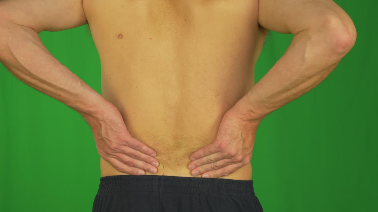 hombre frotando con la palma de la mano la parte inferior de la espalda debido al dolor de espalda.