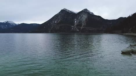 escénica vista aérea baja de 4k sobre el famoso lago walchensee de baviera con su particular agua azul en la campiña bávara rural con un hermoso cielo azul y las montañas de los alpes en el fondo