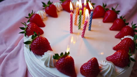 birthday cake with strawberries and lit candles
