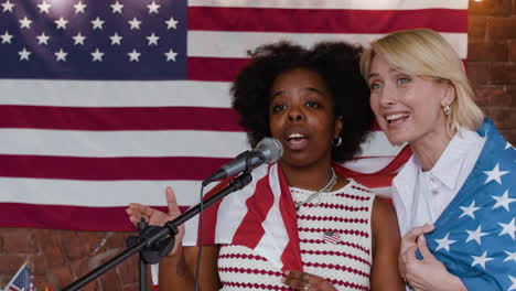 women singing patriotic song in front of american flag