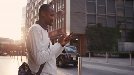 Hombre-De-Negocios-Afroamericano-Caminando-Por-La-Ciudad-Usando-Un-Teléfono-Inteligente