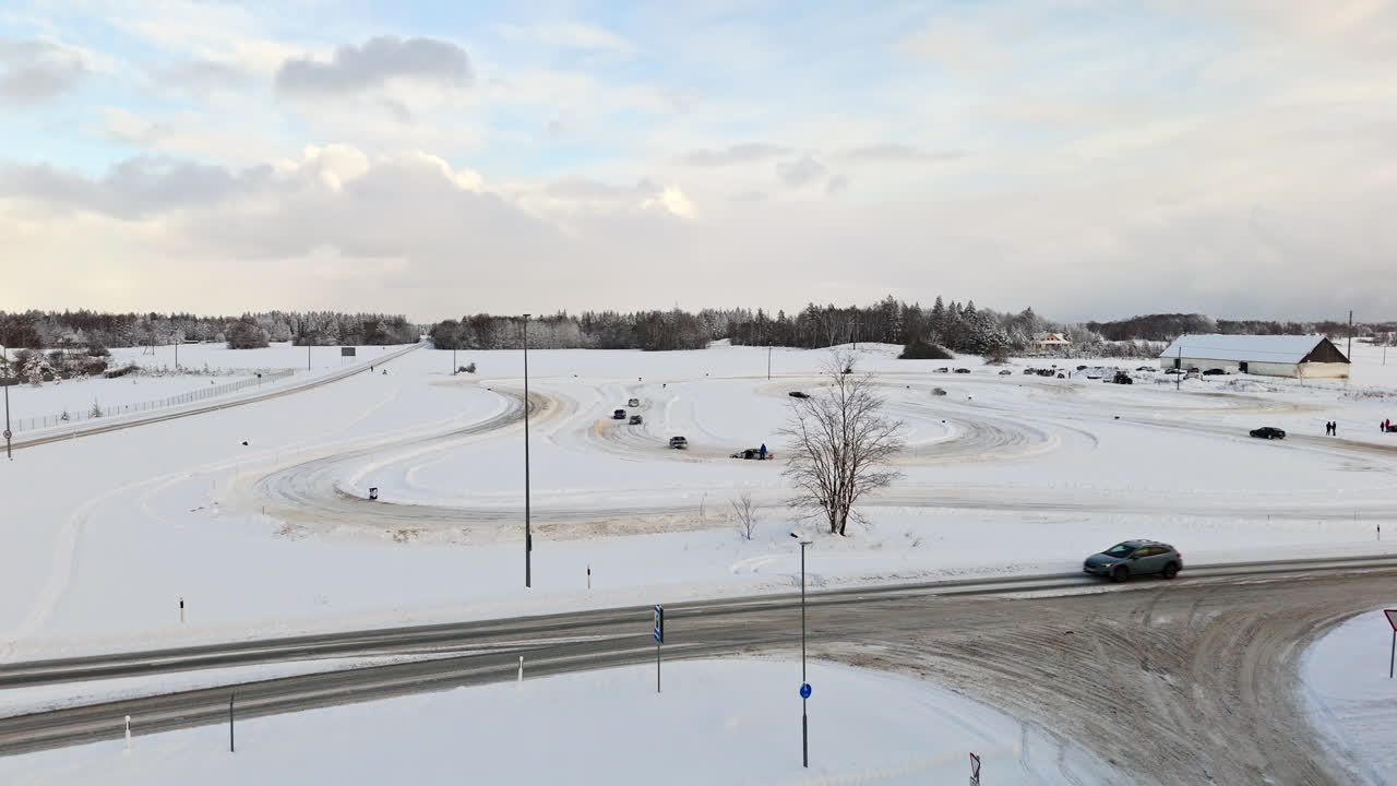 Aerial view approaching cars racing on a ice track, partly sunny, winter evening