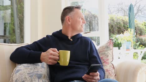 man using mobile phone while having coffee in living room 4k