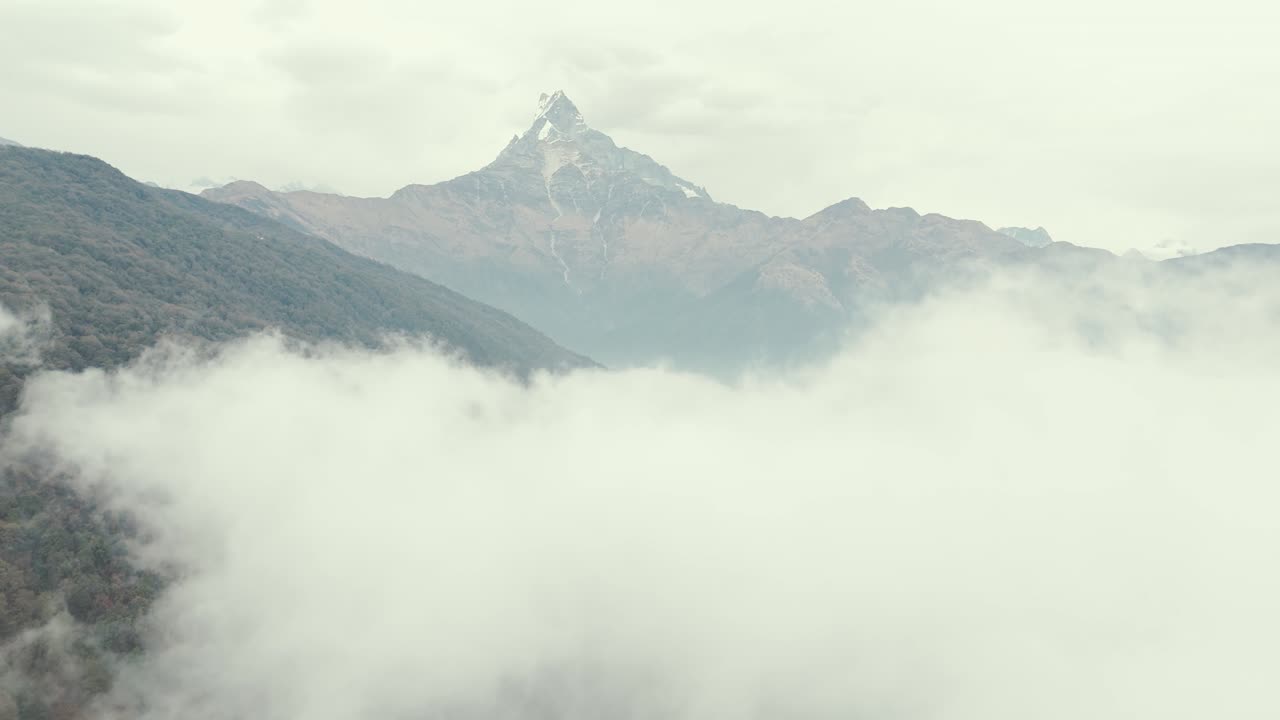 Spectacular aerial ascending through cloud revealing Machapuchare Mountain