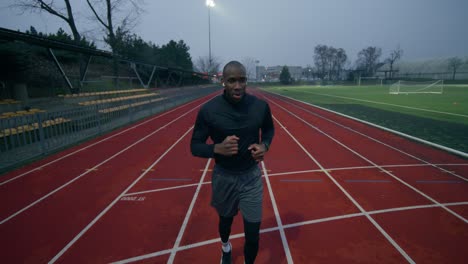 man running on a track at a stadium