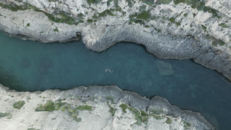 Aerial-top-down-Footage-of-a-swimmer,-in-nature