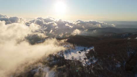 Big-white-clouds-lit-by-sunlight-low-above-winter-forest-landscape