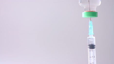 Close-up-of-insulin-vial-and-syringe-on-grey-background-with-copy-space,-slow-motion