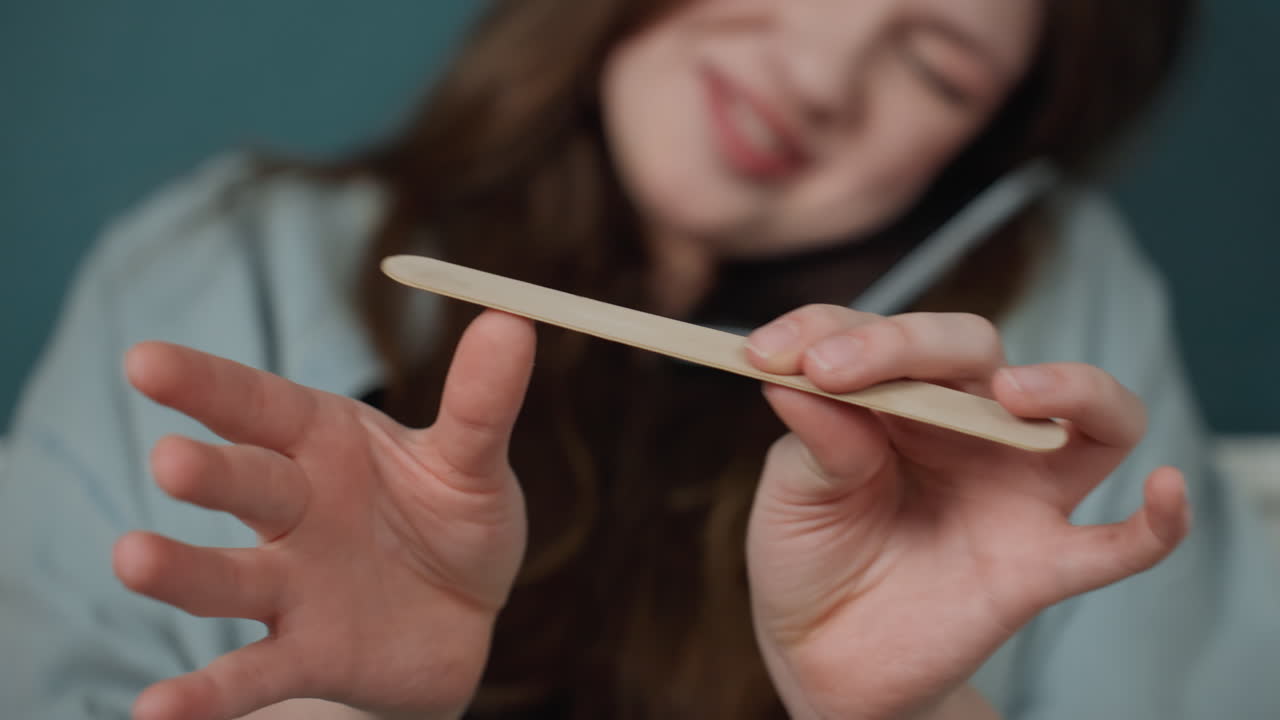 Donna gioiosa che si fa le unghie. Donna luminosa che applica lo smalto con cura. Donna allegra che modella le unghie con movimenti dettagliati. Donna sorridente impegnata in precise attività di manicure in un'accogliente camera da letto.